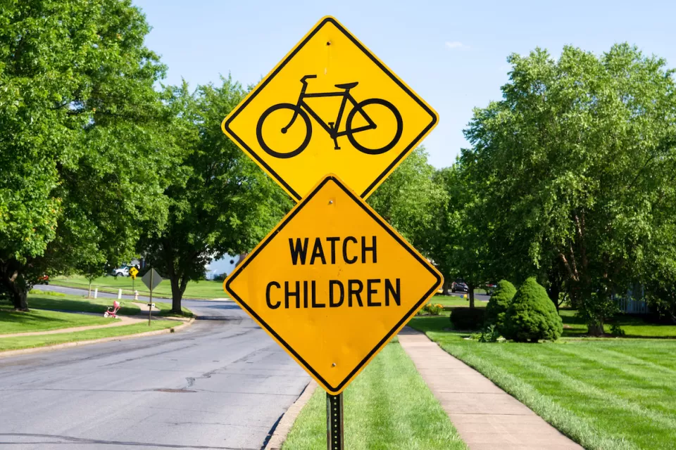 Yellow street sign with bike symbol above yellow 'Watch Children' sign.